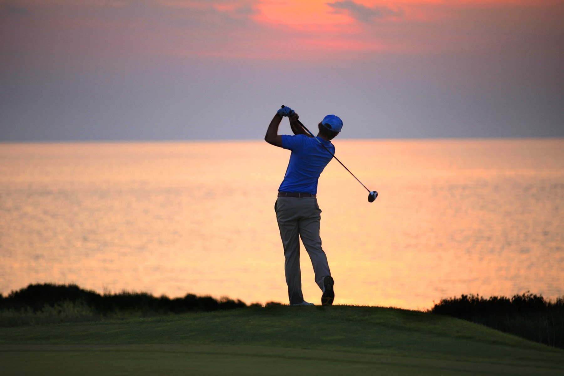 golf-player-swings-bat-while-enjoying-the-sunset-in-golf-course